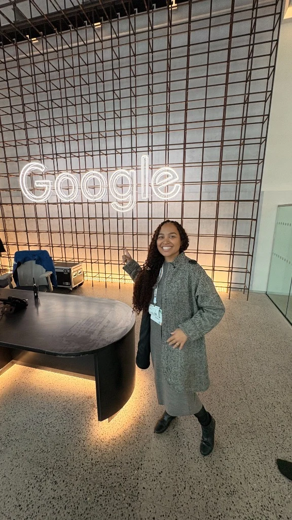 Anna Sánttos apontando para letreiro neon do Google